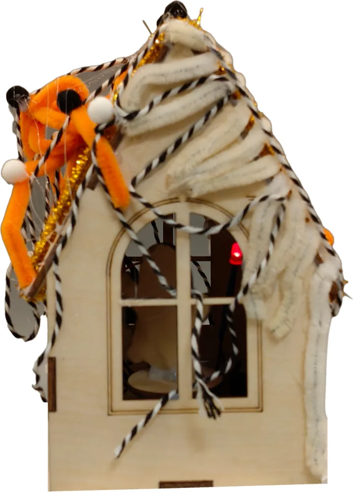 Side view of a haunted house with an arched window and a pipe-cleaner spider on the roof
